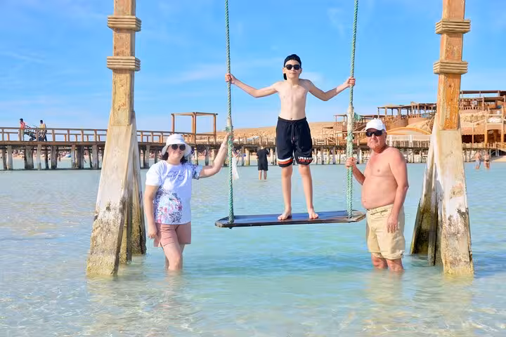 Family enjoying shallow lagoon swing at Orange Bay, Giftun Island stop on Hurghada boat trip with lunch