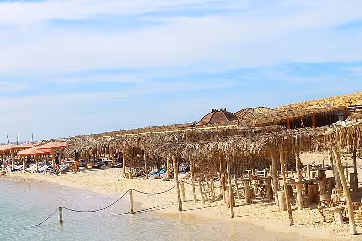 Orange Bay beach on Giftun Island with straw parasols and calm lagoon, Hurghada VIP snorkeling cruise stop