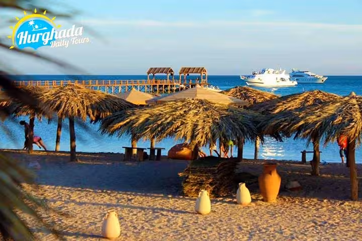 Orange Bay Hurghada seaside with palm huts, wooden pier, and yacht offshore, ideal Giftun Island day trip