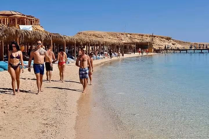 Guests strolling along Orange Bay shoreline on Giftun Island, part of Hurghada VIP cruise with snorkeling