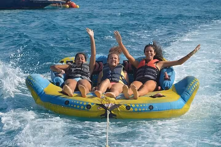Friends riding a towable tube on the Red Sea during Orange Bay VIP cruise from Hurghada water sports