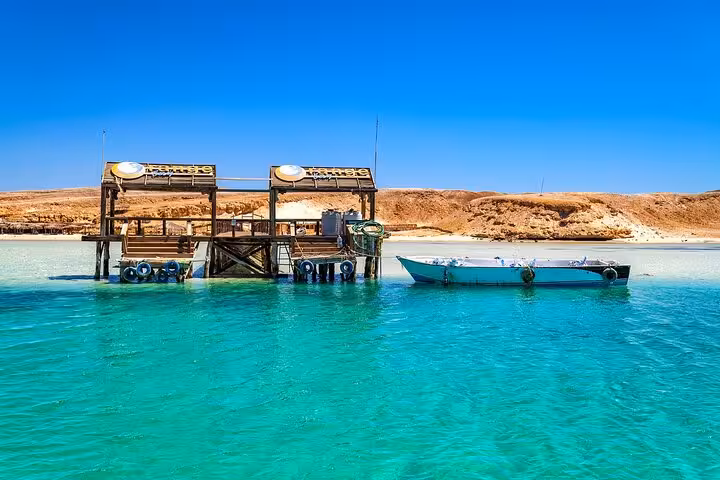 Orange Bay Island pier and speedboat on crystal-clear Red Sea lagoon, private snorkeling trip from Hurghada