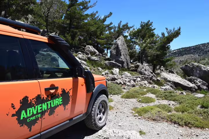 Orange LandRover parked on rugged terrain during VIP Luxury Private Tour in Crete's scenic wilderness.