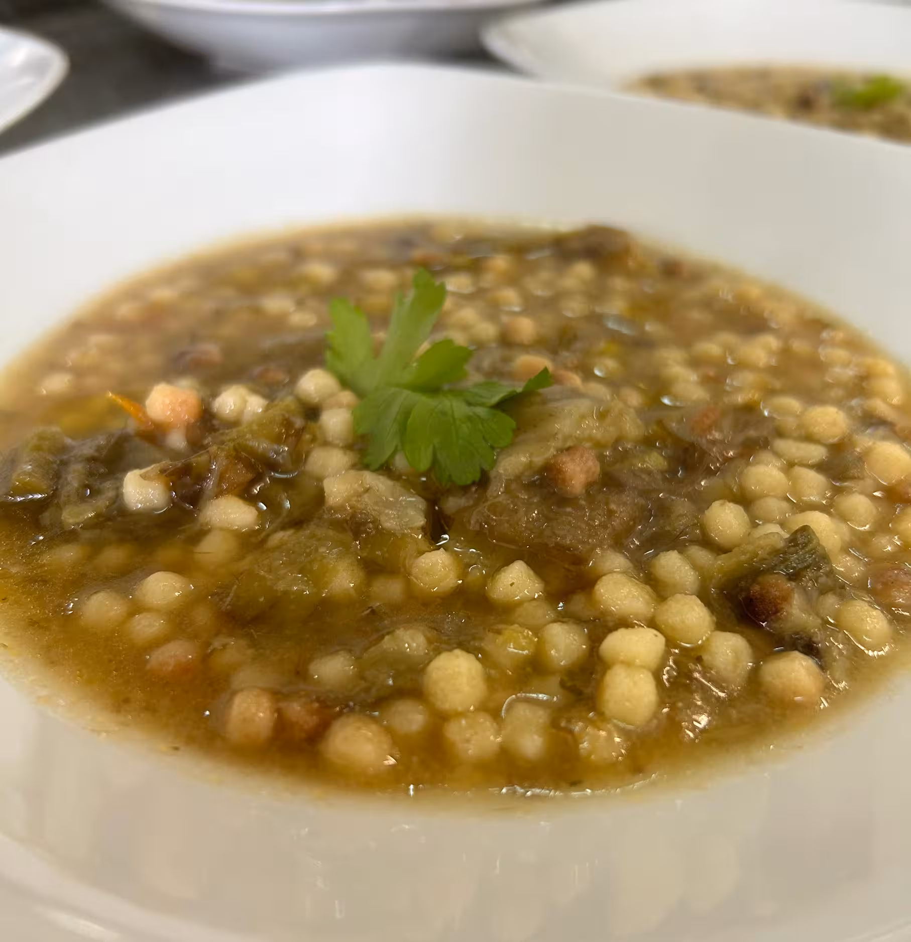 Traditional Sardinian fregola soup garnished with fresh parsley, prepared in an Oristano pasta workshop experience.