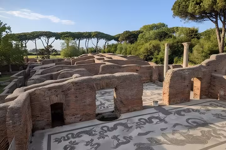 Discover intricate mosaics and ancient architecture amidst lush greenery at Ostia Antica during a private tour.