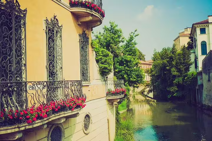 Romantic canal view in Padua with ornate balconies and flowers, seen on a private personalized guided walking tour route