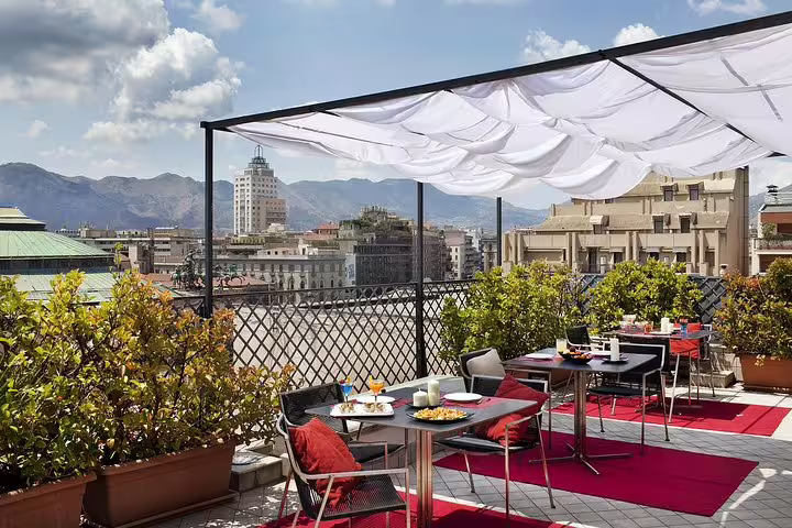 Rooftop terrace at Hotel Plaza Opéra in Palermo with city and mountain views, ideal for relaxing after airport transfer