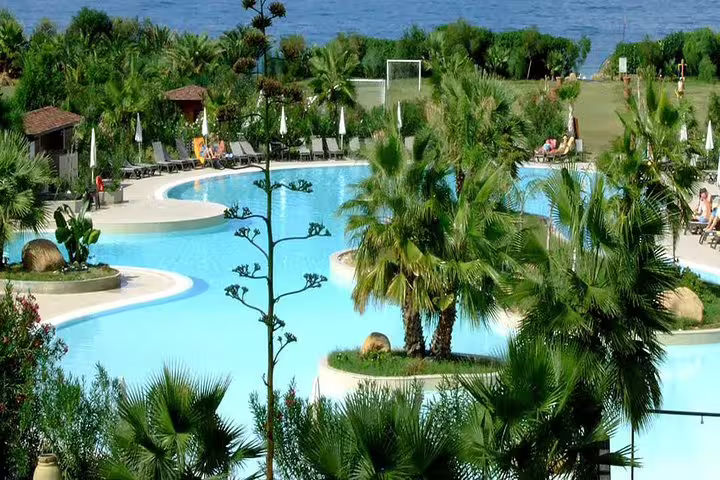 Tropical poolside area at Campofelice di Roccella resort near the sea, reached by private transfer from Palermo airport