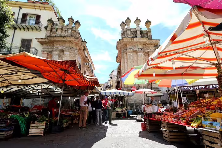 Colorful Ballarò street market stalls and historic city gate in Palermo, Sicily, visited on a 4-hour private shore excursion