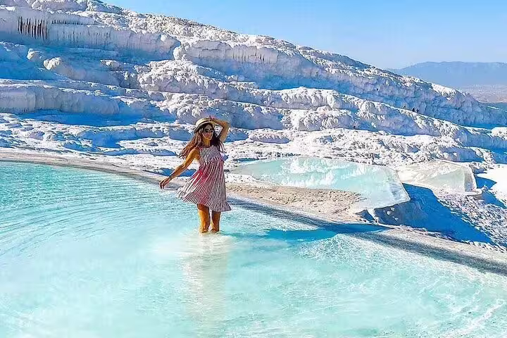 Tourist enjoying the turquoise thermal pools of Pamukkale, a highlight of the small group tour from Izmir.