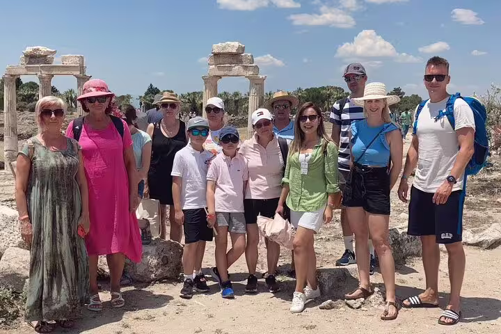 Tour group poses in front of ancient ruins during Pamukkale tour from Izmir under a clear blue sky.
