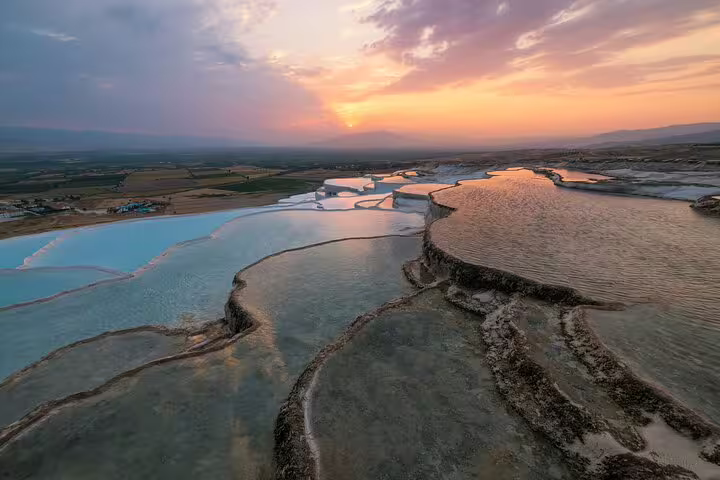 Stunning sunset view over the natural travertine terraces of Pamukkale, showcasing the unique geological formations.