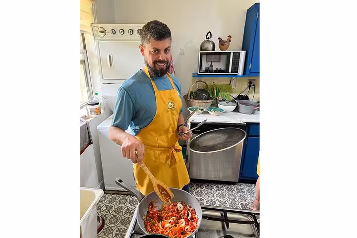 Chef in a yellow apron stirring a vibrant vegetable stir-fry in a cozy Panamanian kitchen for a cooking class.
