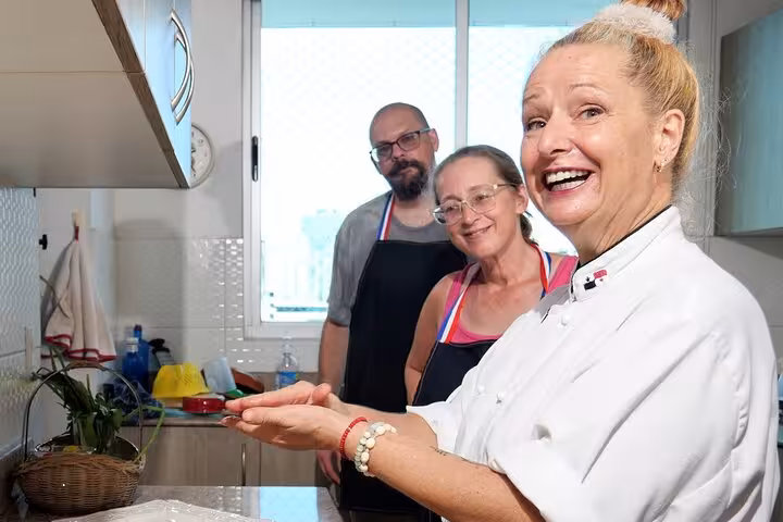 Chef guiding two guests in a bright kitchen during a boozy Panamanian cooking class experience.