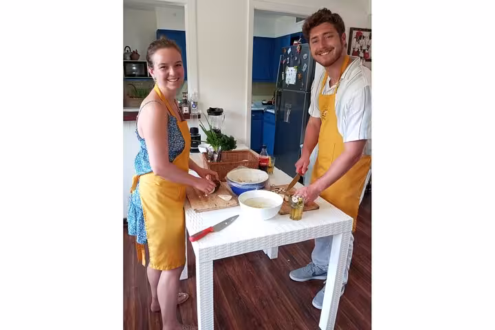 Two participants in aprons enjoy hands-on cooking at the Boozy Panamanian Eat-as-you-Cook Class.