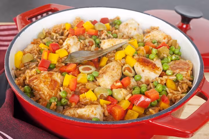 Colorful Panamanian chicken and rice dish with peppers and peas in a red pot, ideal for a culinary class adventure.