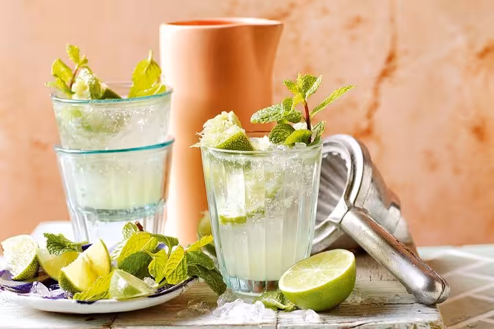 Refreshing glasses of Panamanian mojitos garnished with lime and mint, set on a wooden table with a citrus squeezer.