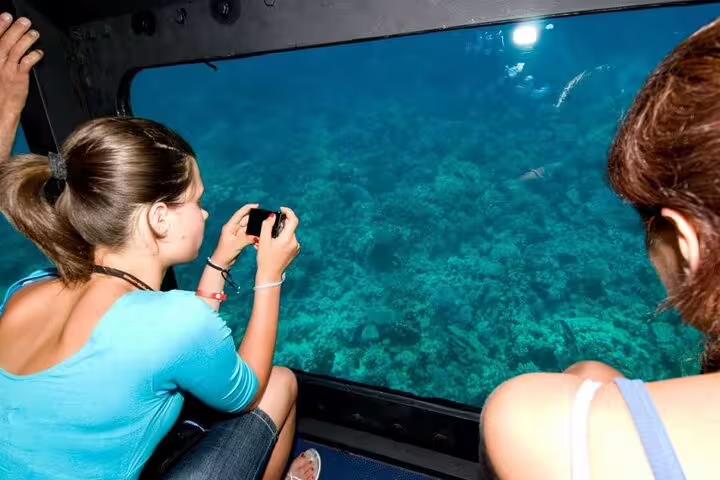 Guest photographing Red Sea coral reef through panorama semi submarine window on Hurghada snorkeling trip