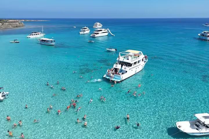 Boat with slide at Akamas Blue Lagoon, Cyprus, with snorkeling swimmers on Paphos bus and boat transfer