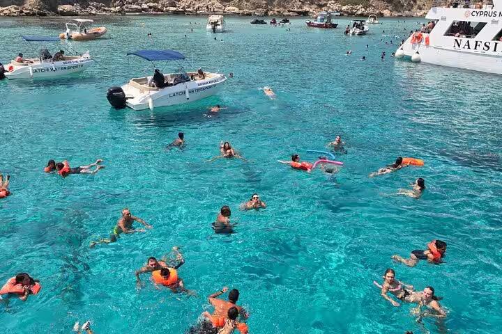 Swimmers in crystal-clear Blue Lagoon Akamas, Paphos boat transfer stop with snorkelling and slide fun