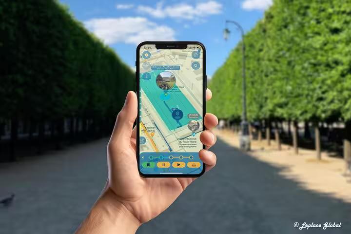 Hand holding smartphone with Paris fashion history walking tour app map in a tree-lined Parisian boulevard