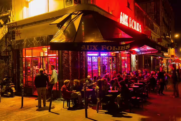 Paris nightlife at Aux Folies, a hidden gem in vibrant Belleville, showcasing lively street dining and vibrant neon lights.