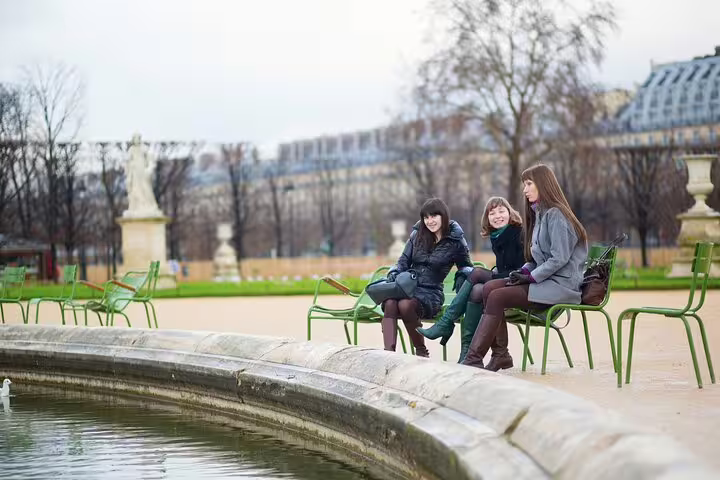 Three women enjoy a relaxing moment by a fountain in a Parisian park, perfect for a private city highlights tour.