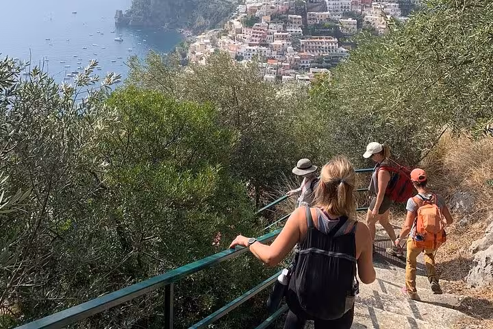 Hikers descending scenic Path of the Gods with panoramic views of Amalfi Coast and Mediterranean Sea.