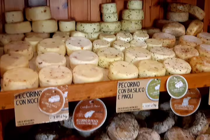Artisanal pecorino cheeses stacked on wooden shelves in a Tuscan shop, sampled on the Good Morning Chianti Classico tour