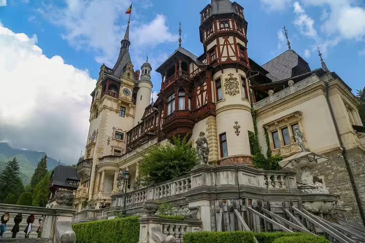 Peles Castle facade with ornate Neo-Renaissance architecture, half-timbered towers, and sculpted terrace in Sinaia, Romania