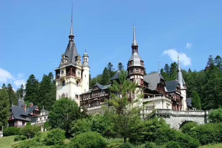 Peles Castle with ornate towers and timber-framed architecture surrounded by green forest in Sinaia, Romania