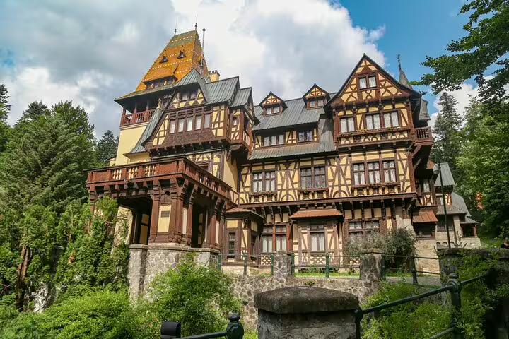 Pelisor Castle Tudor-style architecture surrounded by lush forest trees in Sinaia Romania