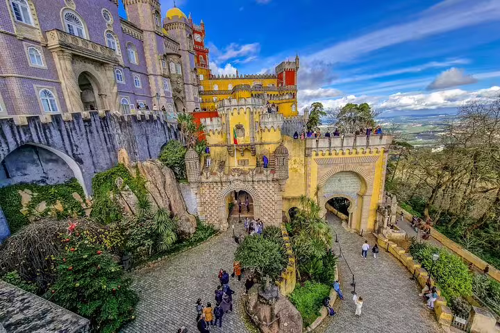 Colorful view of Pena Palace in Sintra, Portugal, showcasing vibrant architecture and lush surroundings on a sunny day.