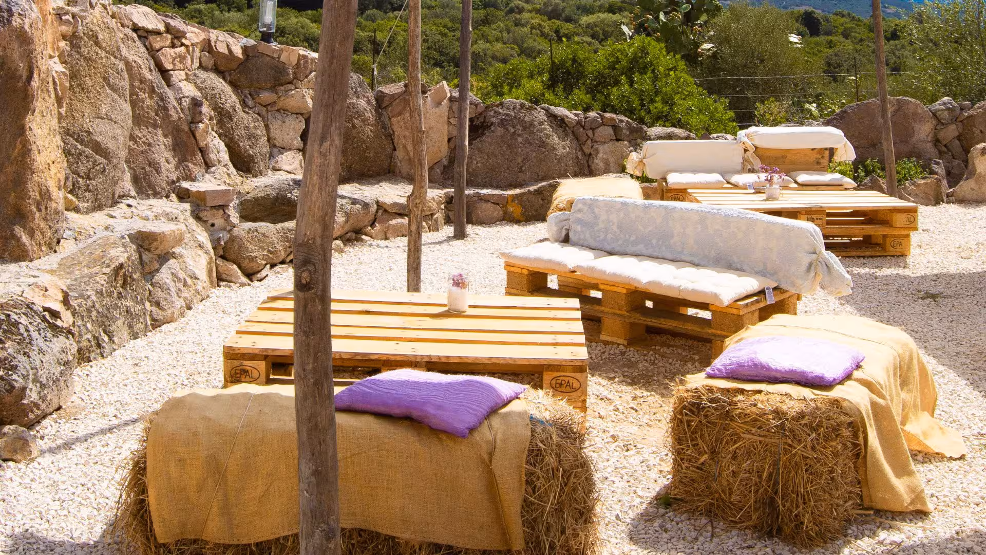 Rustic outdoor lounge with pallet seating and hay bale cushions at Perfugas glamping, ideal for relaxation.