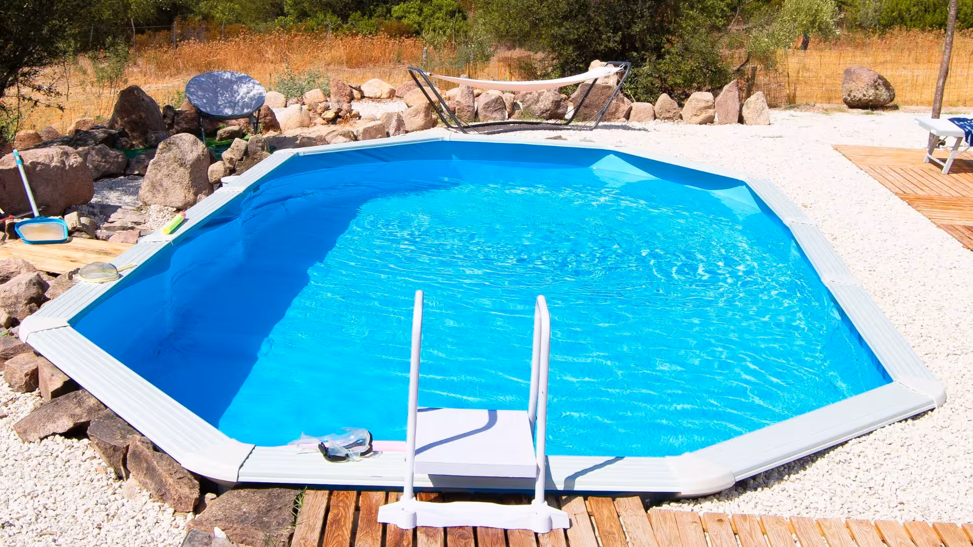 Inviting blue pool with hammock and stone surroundings at Perfugas glamping destination in nature.