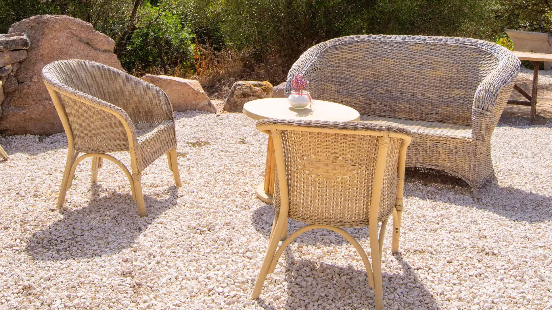 Cozy outdoor seating area with wicker furniture at Perfugas glamping, perfect for a serene nature retreat.