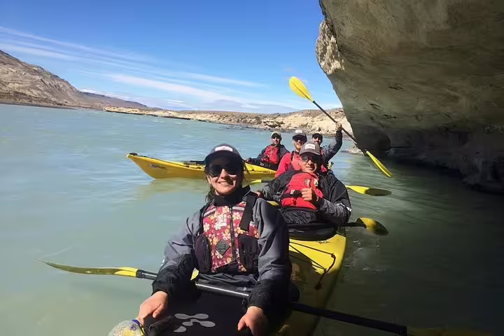 Smiling kayakers navigate the turquoise waters of La Leona River, enjoying the scenic El Calafate landscape.