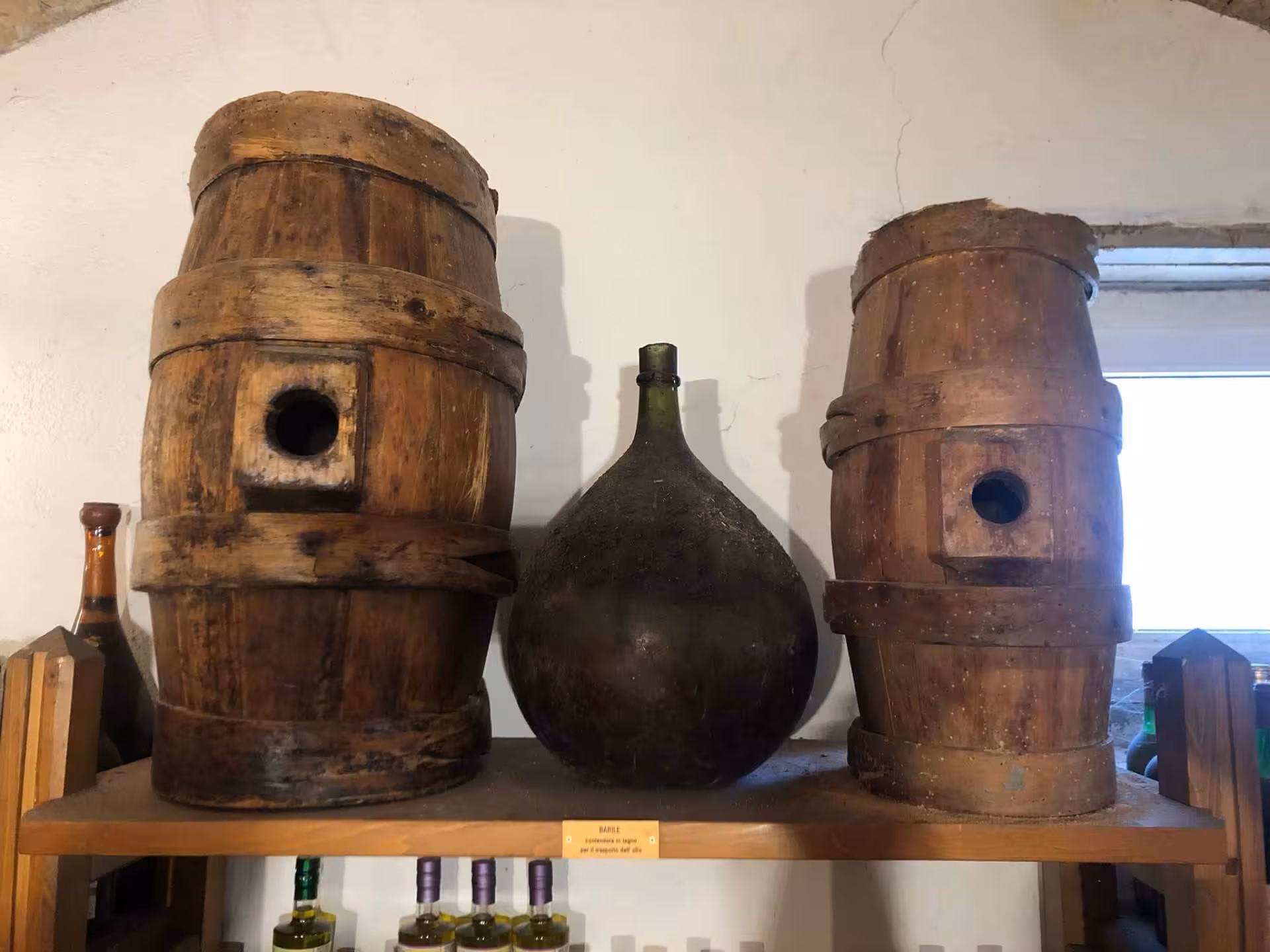Vintage barrels and glass bottle on display at a Perugia olive oil mill during the guided tasting tour.