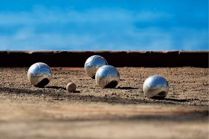 Close-up of pétanque boules and jack on a sandy court during a Marseille pétanque tour experience