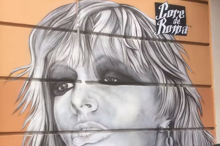 Street art mural in Pigneto, Rome, featuring a monochrome portrait, part of the craft beer tour's cultural exploration.