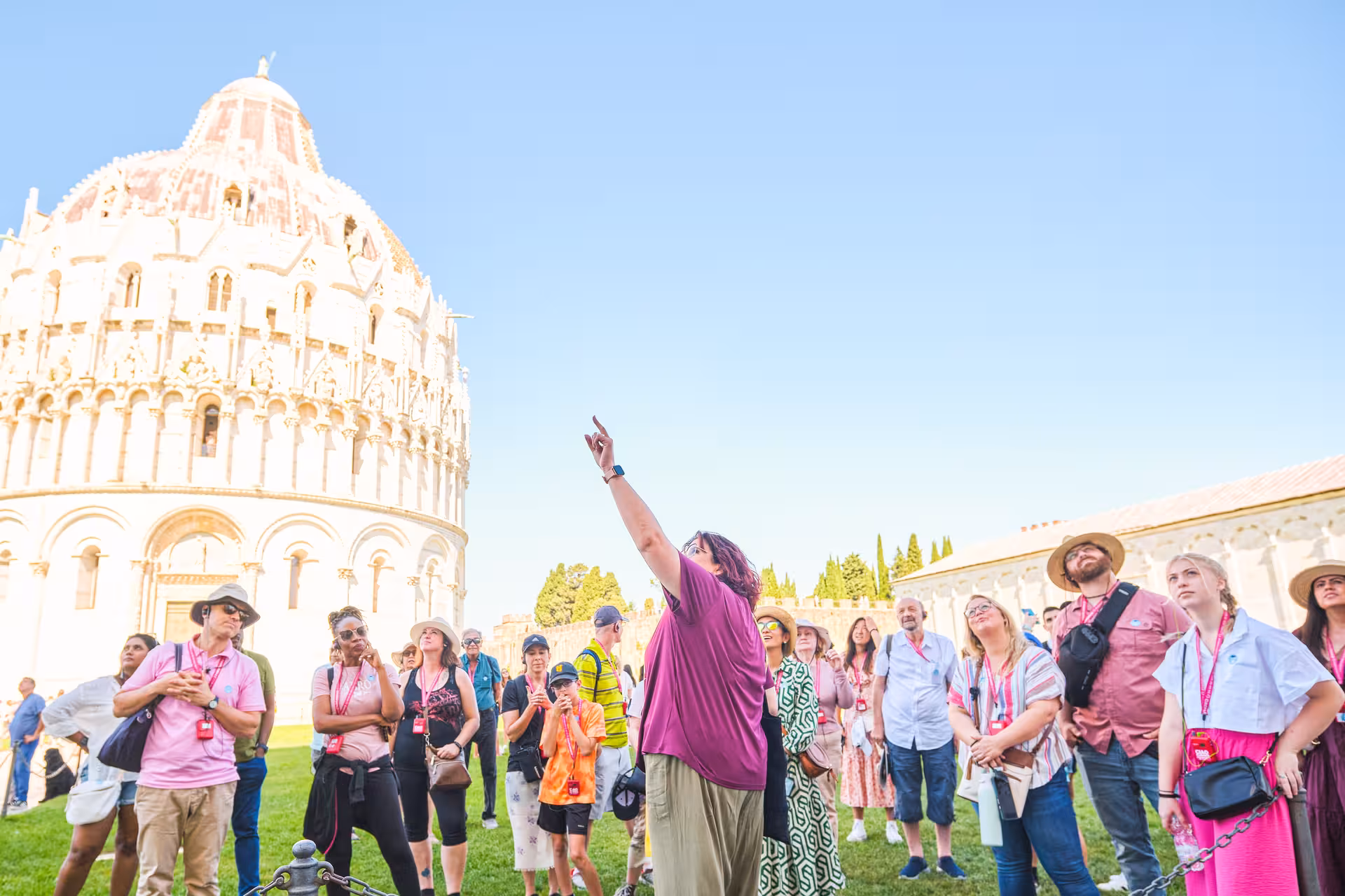 Guide explaining Pisa's Baptistery to a group of tourists on a cultural shore excursion from Livorno.