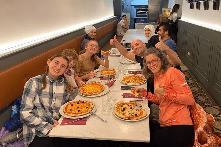 Group enjoying homemade pizzas during a cooking class near Piazza Navona in Rome, showcasing authentic Italian cuisine.