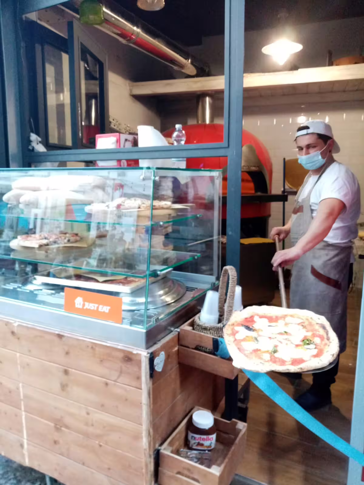 Pizzaiolo in Naples prepares traditional Margherita pizza in wood-fired oven on Pino Daniele themed walking tour stop