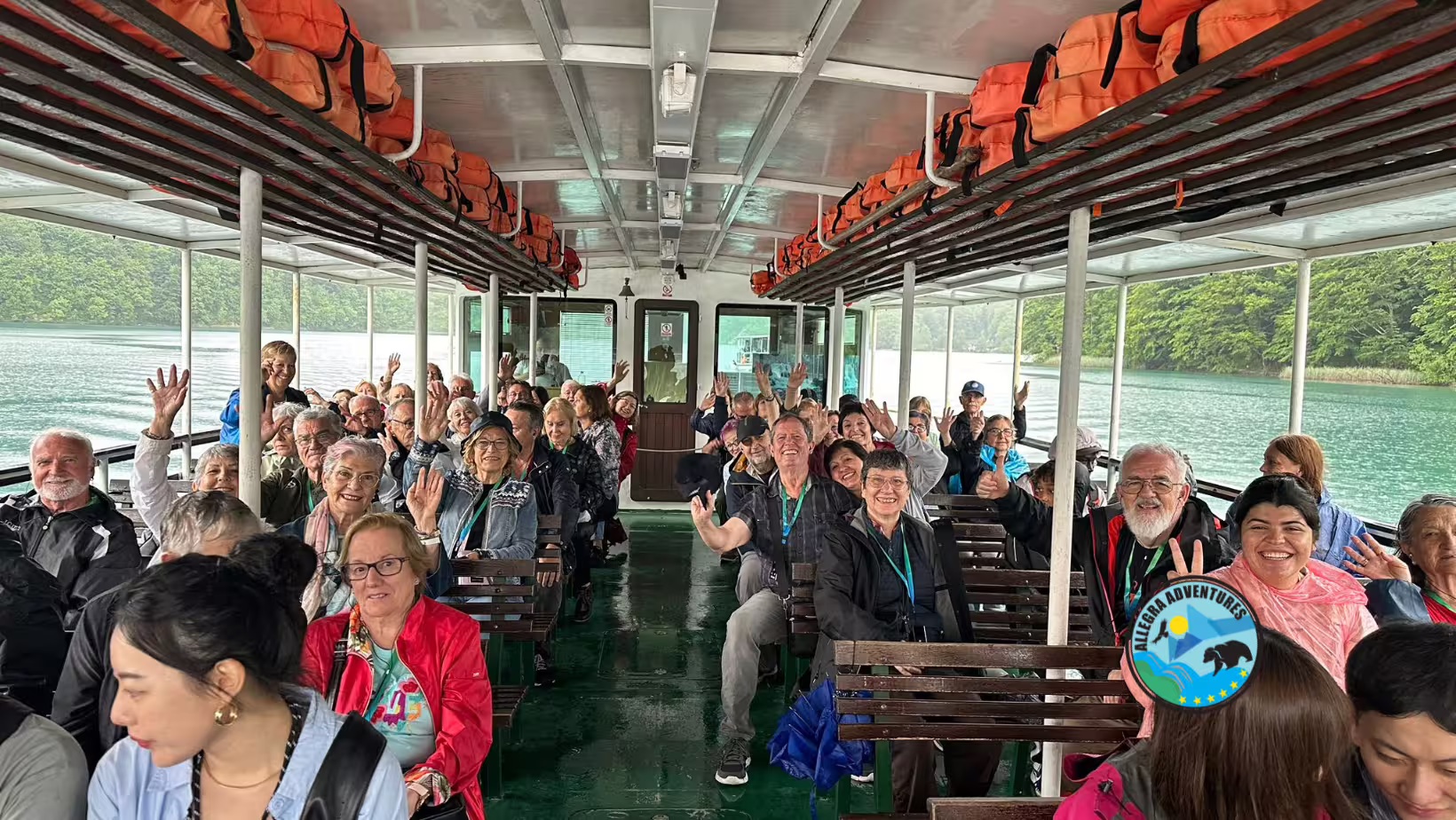 Happy group on Plitvice Lakes electric boat ride with secured entry tickets, cruising the turquoise lake