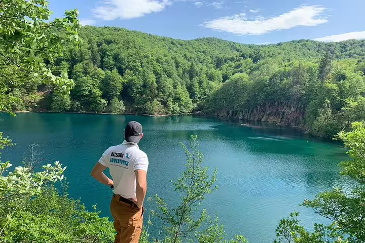 Traveler at Plitvice Lakes viewpoint above emerald water, part of secured tickets tour with panoramic train and boat ride