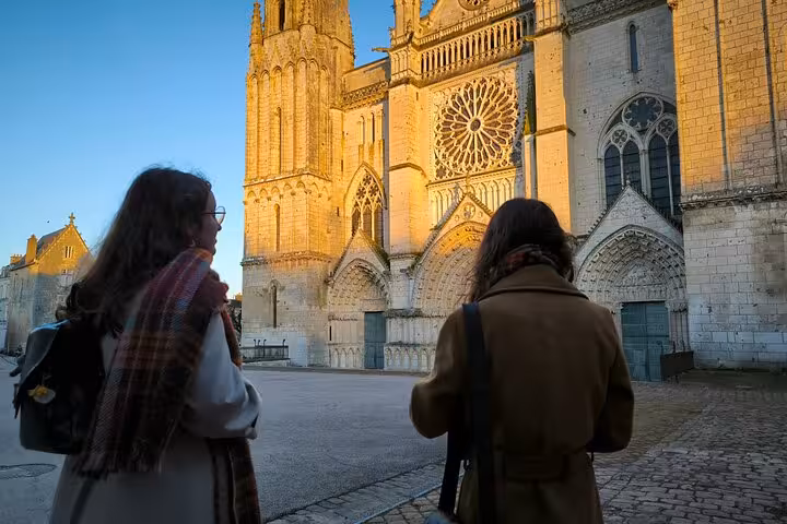 Two visitors admiring the illuminated facade of a grand cathedral in Poitiers at sunset.