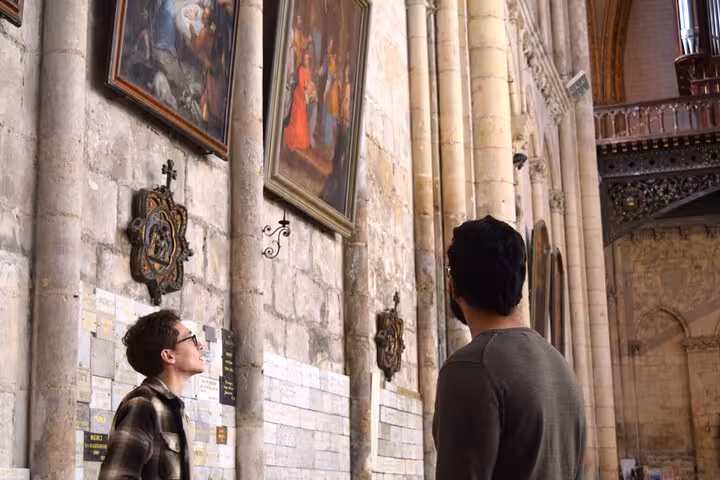 Two men admire historic paintings on the walls of a grand cathedral during a Poitiers walking tour.