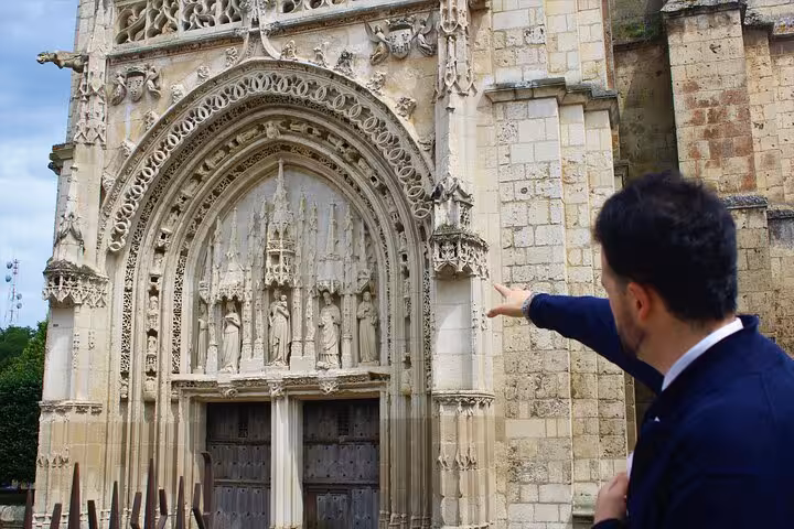 Guide pointing at the intricate facade of a historic church during a walking tour in Poitiers.