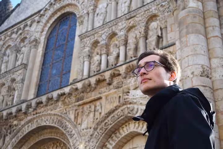 A visitor admires the intricate Romanesque facade of a historic church during a walking tour in Poitiers.