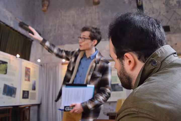 Tour guide gestures while explaining historic exhibits to a visitor inside a Poitiers heritage site.
